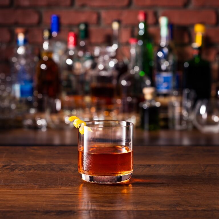 Sazerac cocktail served on a bar with an orange peel garnish