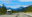 Motorhome driving along a scenic road in Canada, surrounded by lush forests and distant mountains under a bright blue sky