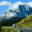 RV travelling along a scenic road in Canada with snow-covered mountains towering in the background under a clear sky.