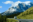 RV travelling along a scenic road in Canada with snow-covered mountains towering in the background under a clear sky.