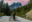 Cyclist Cyclist standing on a mountain road with a bike, gazing at snow-covered peaks under a colorful sky.