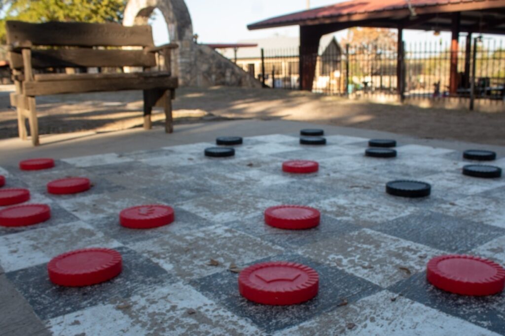 Outdoor giant checkers game at Mayan Dude Ranch in Bandera, Texas, offering fun family-friendly activities in a scenic Hill Country setting.