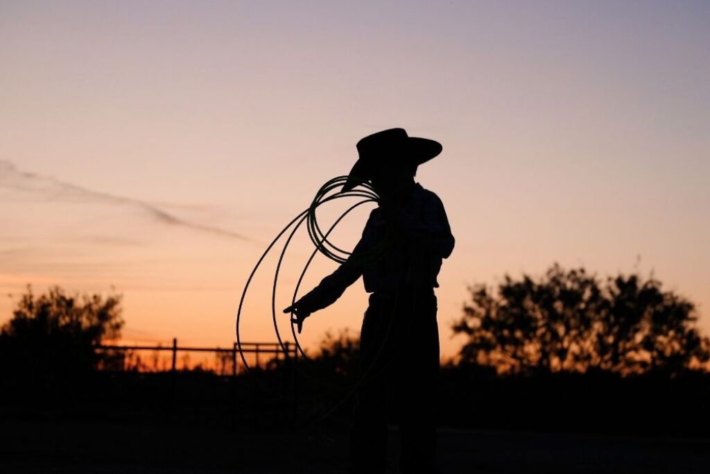 Young cowboy with rope in Texas sunset on ranch