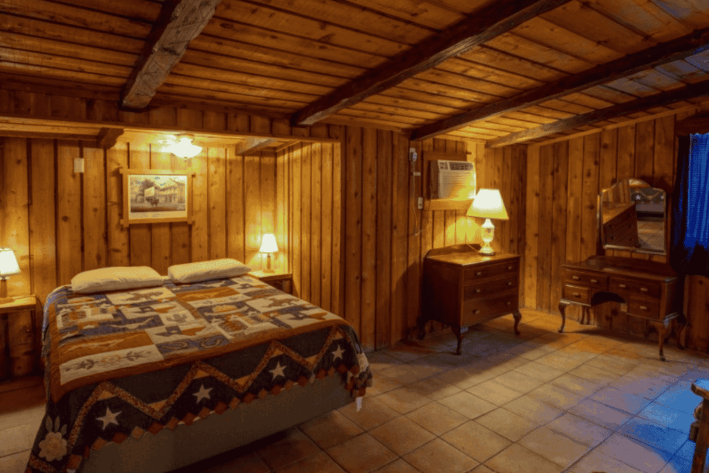 Cozy double bedroom at Mayan Dude Ranch in Bandera, Texas, featuring rustic timber accents, handmade quilts, and a porch overlooking Hill Country.