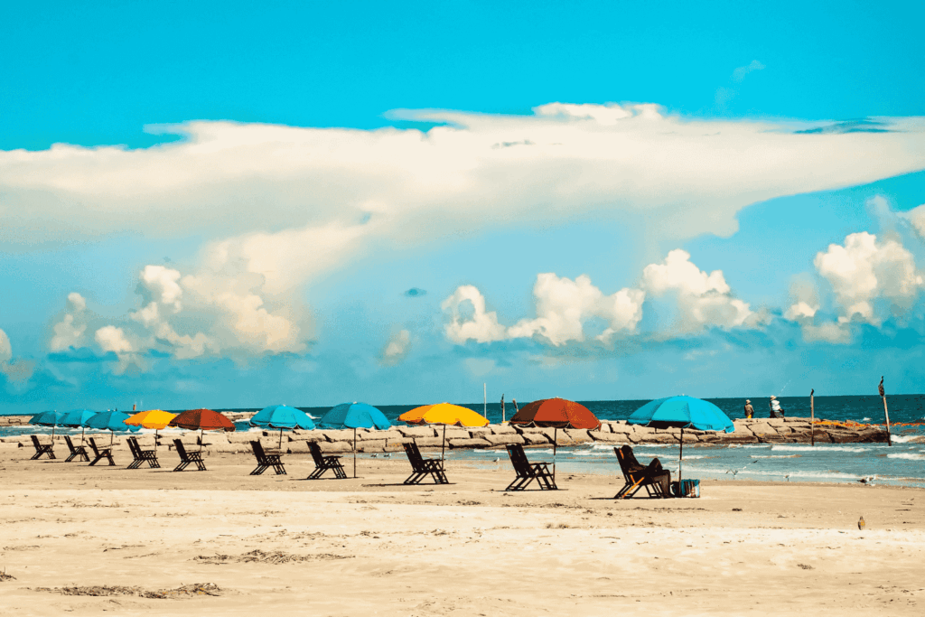 A row of colorful beach umbrellas and beach loungers on Galveston Island Texas.
